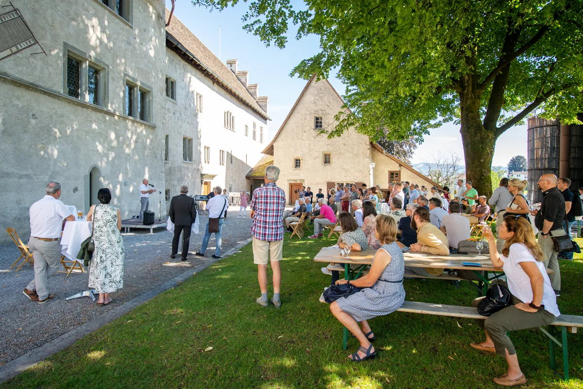 Viele Leute sitzen auf Bänken im Hof des Ritterhauses Bubikon.